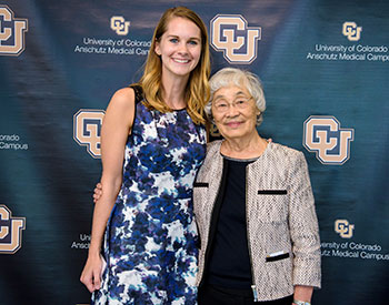 Scholarship Recipient Marissa Yoder poses for a photo with Dr. Furukawa in front of a CU backdrop
