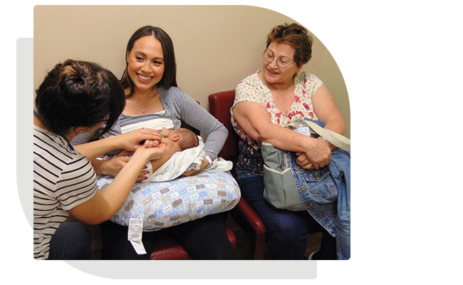 Midwife with patient and baby showing how to feed baby