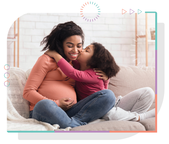 pregnant woman smiling with child kissing her cheek