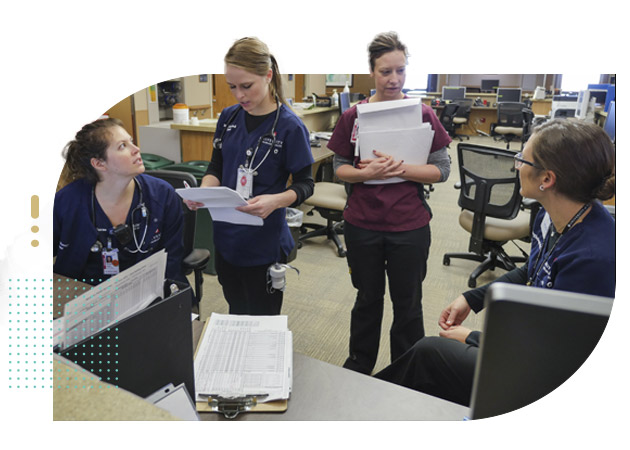 Group of nurses at hospital station reviewing charts