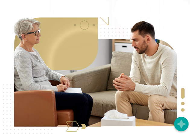 Senior woman nurse talking to young man patient at psychotherapy session