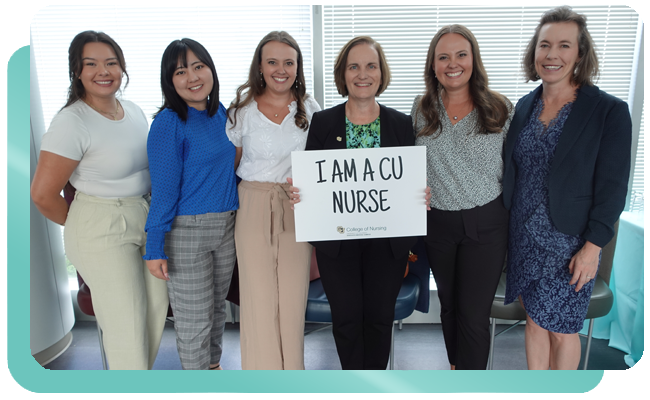 Group of young women with instructor holding 'I Am a CU Nurse' sign