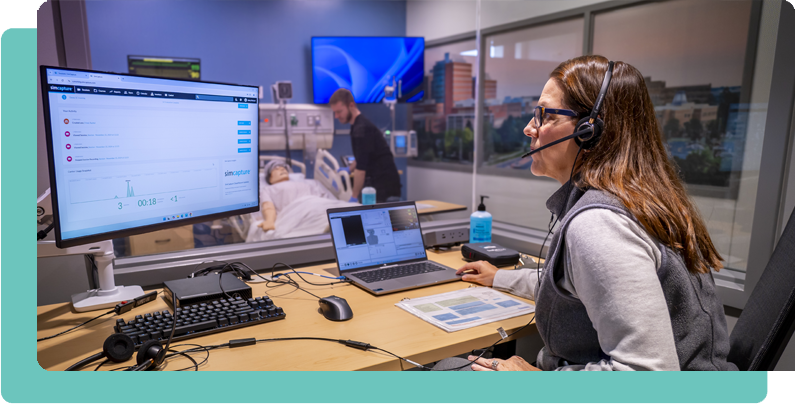 Woman in simulation control watching college nursing student